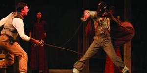 Men sword fight on stage