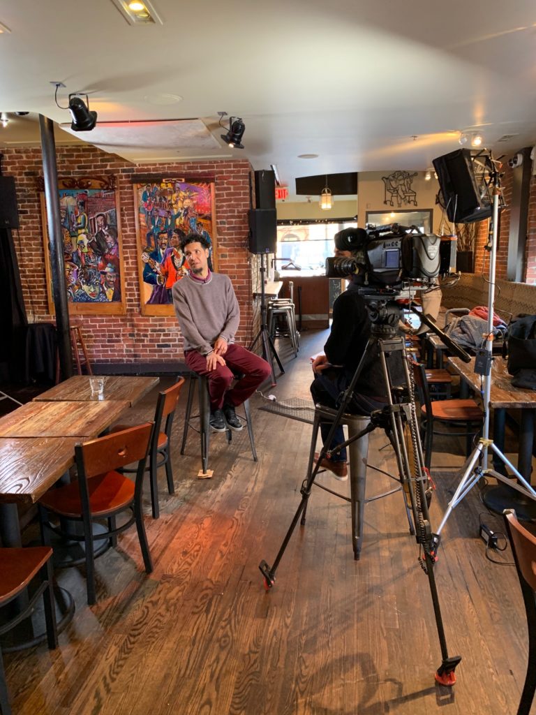 A film crew interviewing Will Power inside Darry'ls Kitchen and Bar in Boston. 