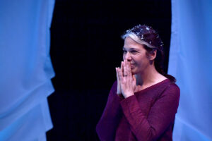 Melinda Lopez performing in Mala with her hands in a prayer position held up to her lips.