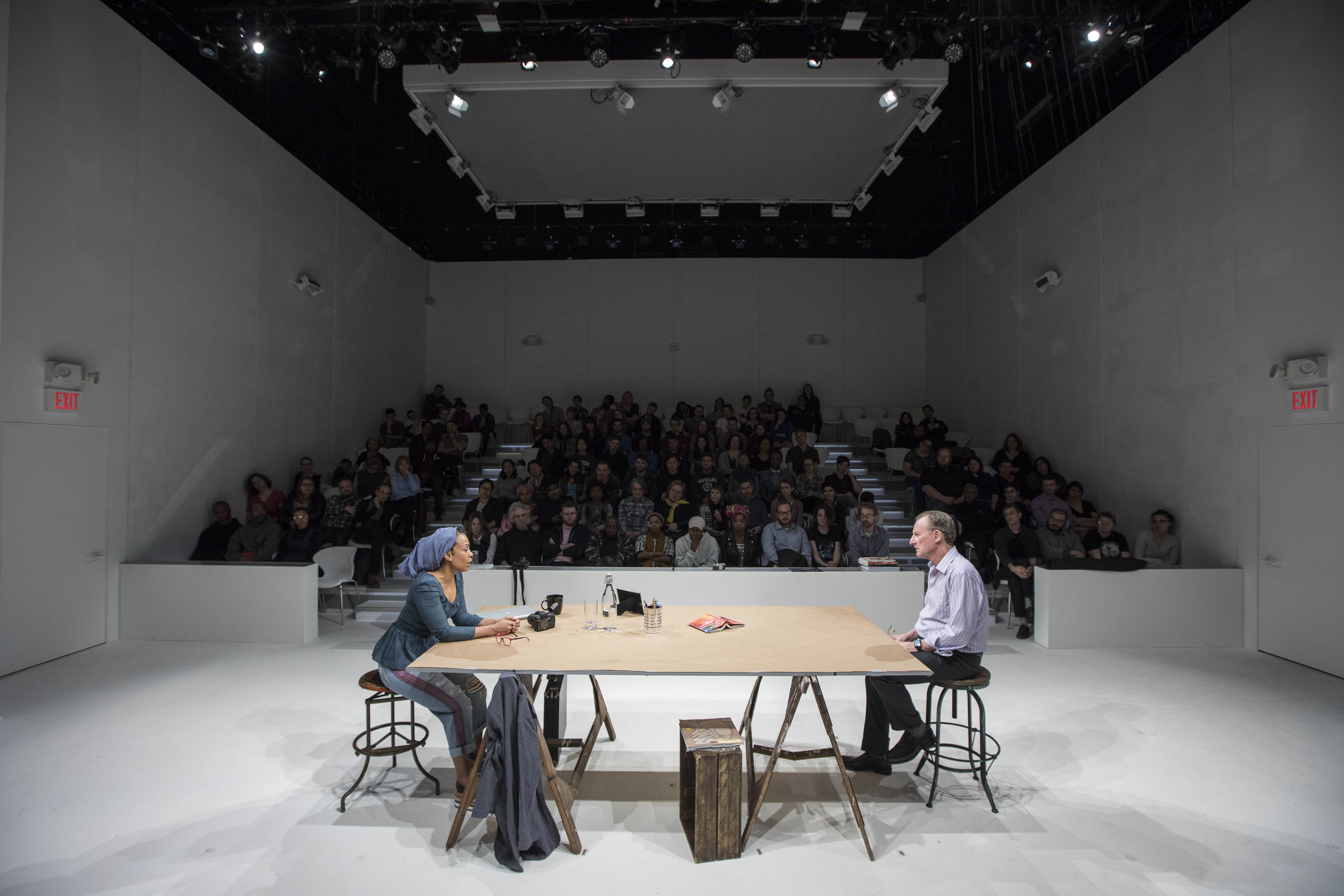 Charlotte and Charles sit opposite a table in her studio.