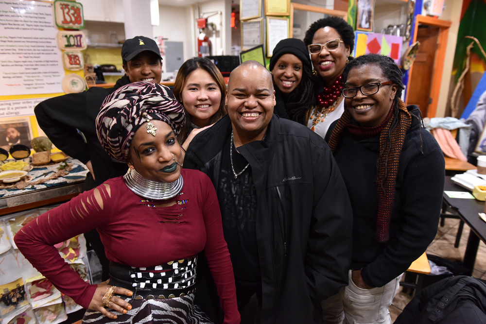 Boston artists (left to right) Nahdra Ra, Kendra Hicks, Ngoc-Tran Vu, Melissa Alexis, Latifa Ziyad and Letta Neely meet with Toshi Reagon (center) at Dorchester’s Oasis Vegan Veggie Parlor to discuss the Parable Path Boston. (Photo: Craig Bailey/Perspective Photo)