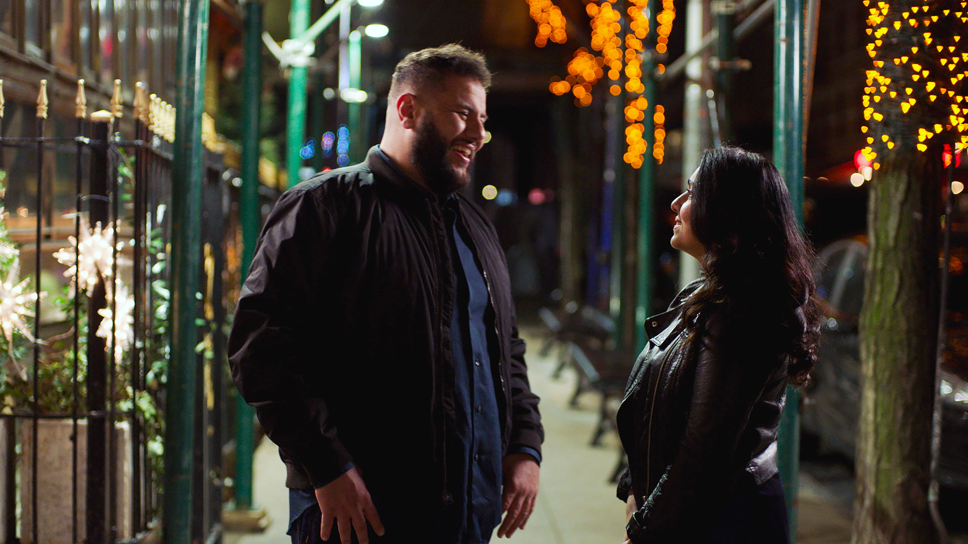 Two people smiling and talking outside at night