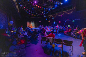 Lights are dimmed in the theatre for a party scene