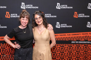 Audience members posing for a photo in front of the ArtsEmerson logo
