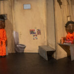 Puppets in orange in a prison cell