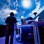 Person standing in front of projection of planet earth