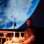 Person standing in front of projection of planet earth