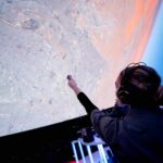 Person standing in front of projection of planet earth