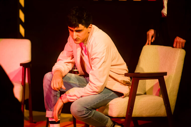 Actor AArian Mehrabani sitting in a white chair slouched over.