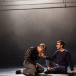 Two men sitting together, one kissing the other's hand.