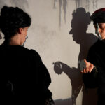 Two actors in front of a screen, shadows projected onto the screen