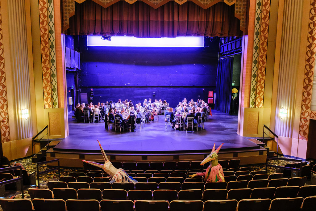 Life-sized puppets watching patrons at dinner from the theater seats
