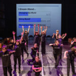 Children on stage with their arms raised
