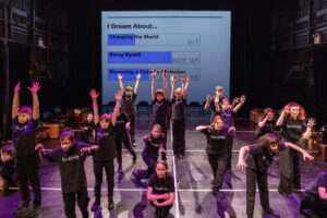 Children on stage with their arms raised