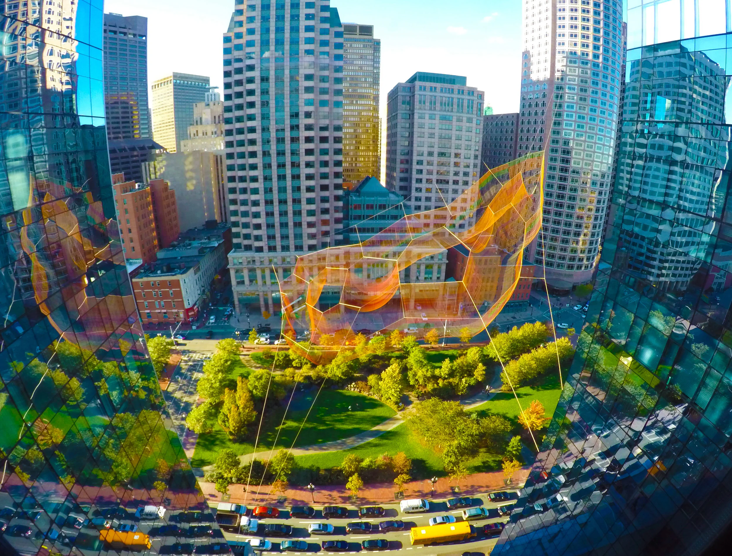 Net sculpture in the middle of a park with green grass. Shot taken from aerial view.