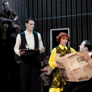 10 years ago we presented  Lebensraum (Habitat). Who remembers this show? #FlashbackFriday 
.
.
.
Image description: Two men in white shirts and black vests. A woman in a yellow dress reads the newspaper. A man sitting on a wardrobe is playing the guitar.
